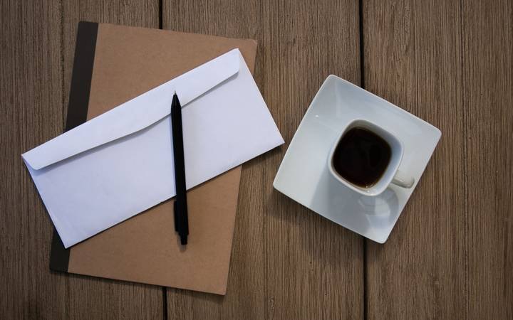 Envelope pardo e caneta sobre uma mesa de madeira