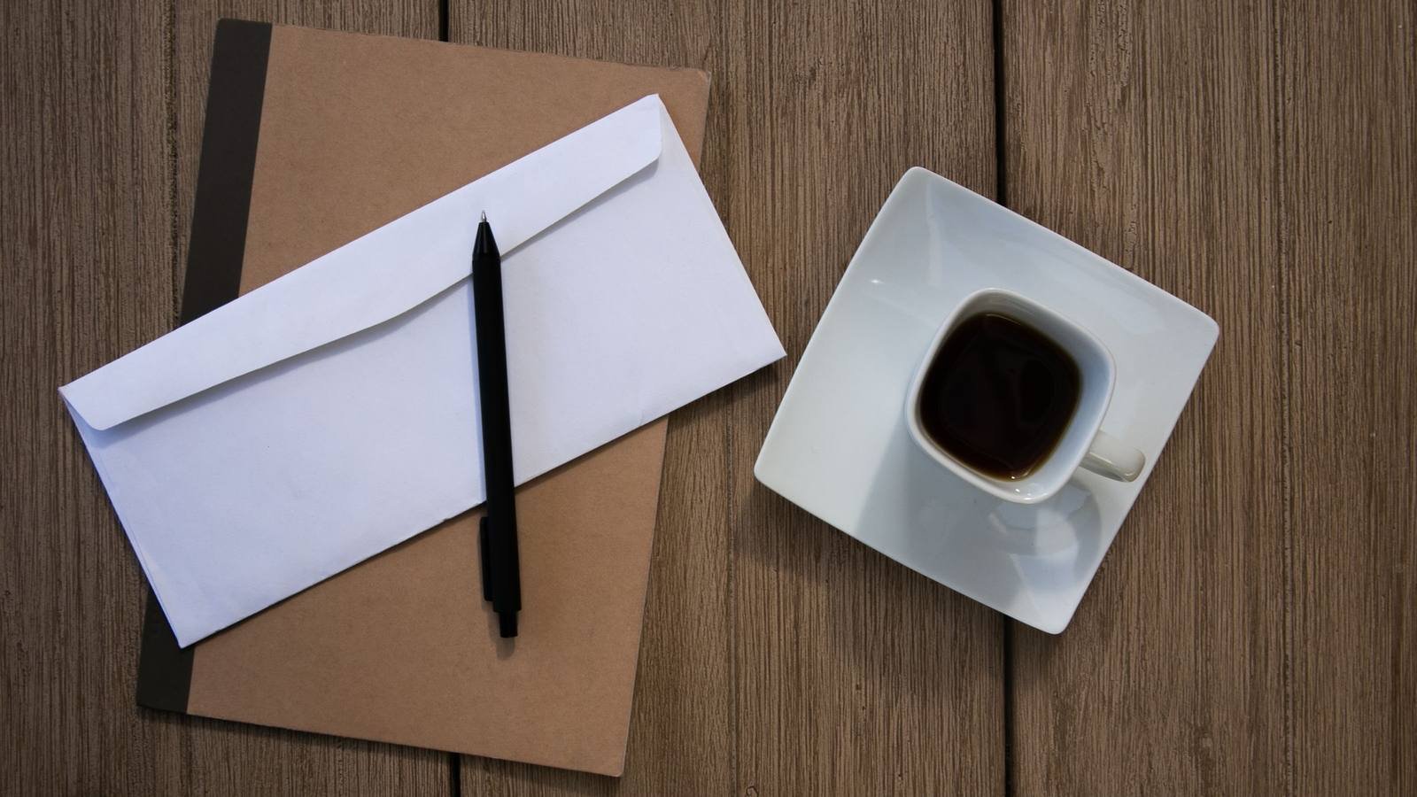 Envelope pardo e caneta sobre uma mesa de madeira