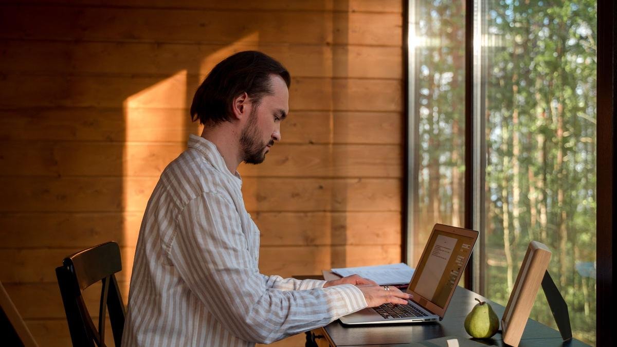 Profissional trabalhando em um notebook, junto a uma janela
