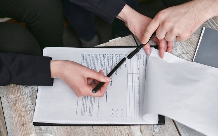 Duas pessoas conferindo um documento sobre uma mesa de trabalho