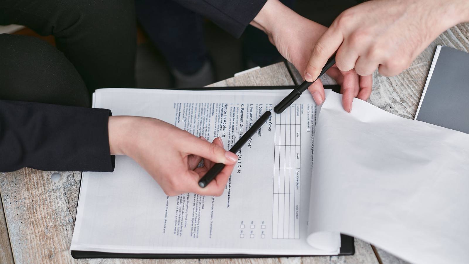 Duas pessoas conferindo um documento sobre uma mesa de trabalho