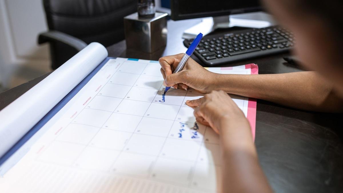 Mão anotando uma data em um calendário de mesa