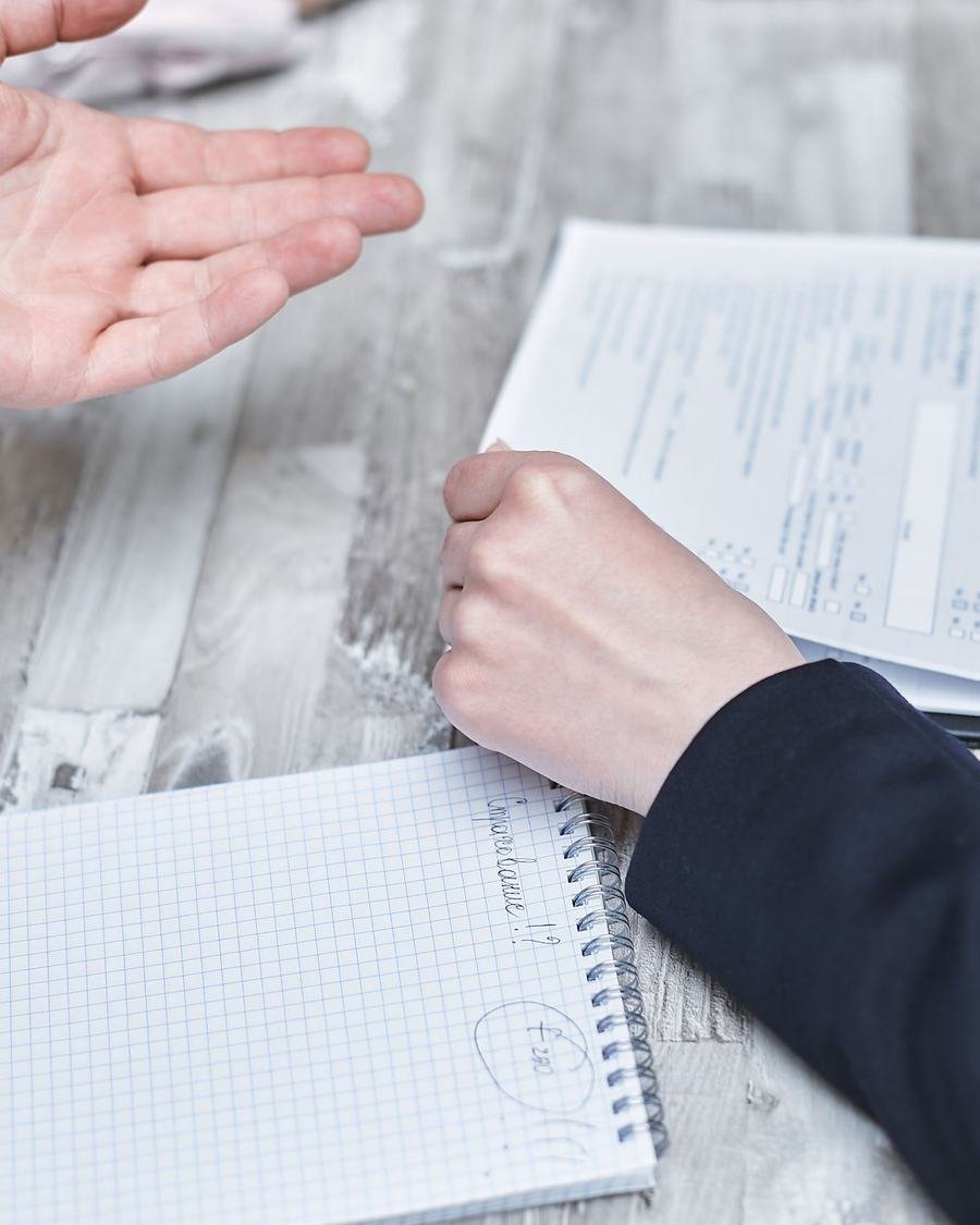 Mãos apontando um trecho de um documento sobre uma mesa de trabalho