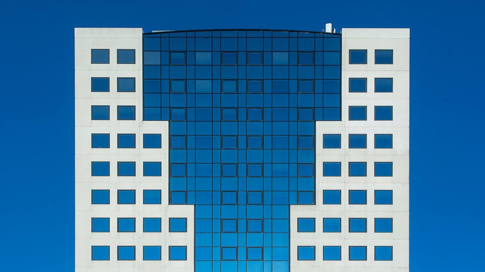 Fachada de um edifício corporativo moderno, em vidro azul, contra o céu