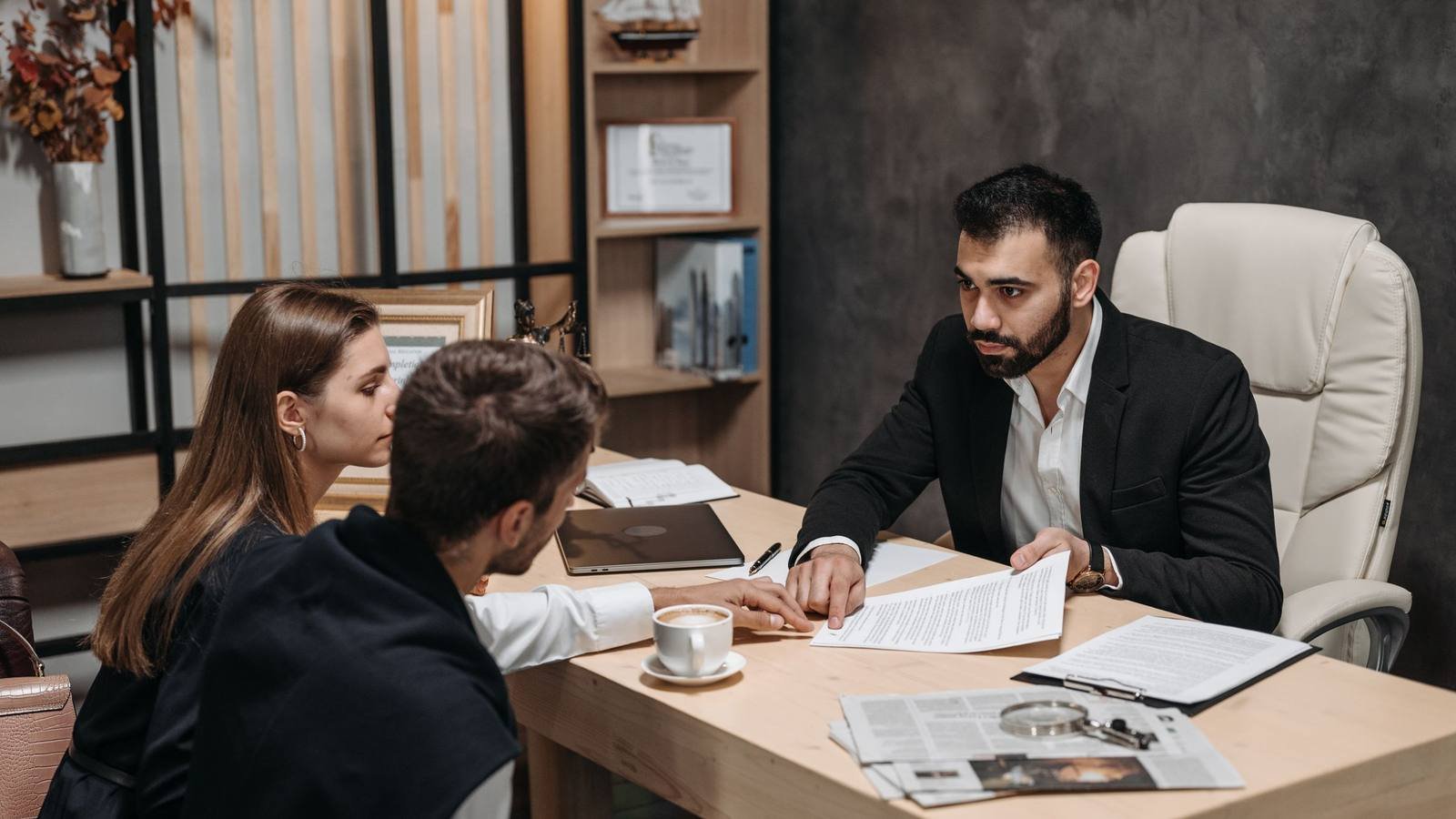Atendimento de consultoria tributária: dois clientes analisam documentos com um consultor, à mesa de um escritório