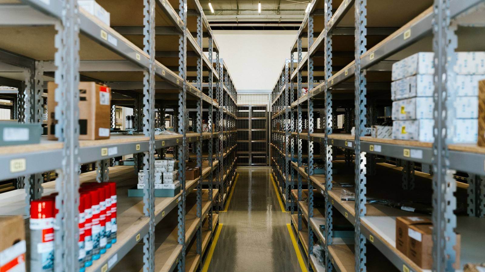 Corredor de um galpão de estoque, com mercadoria organizada nas prateleiras